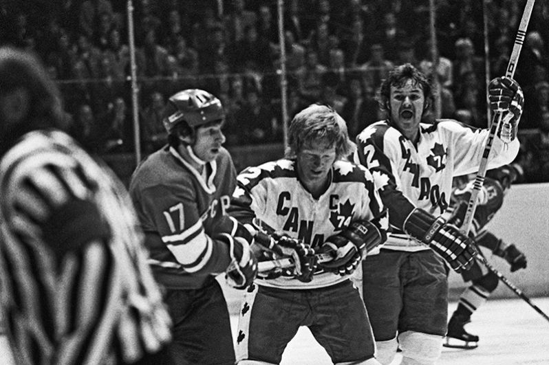 Советский хоккеист Валерий Харламов (слева) и канадский хоккеист Пэт Степелтон (в центре) в борьбе за шайбу во время матча хоккейных команд СССР и Канады. 1974 год.
