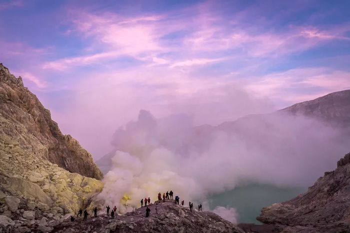 Photo of people standing on a cliff with the beautiful purple sky above
