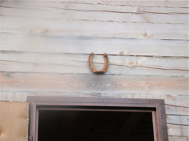 A horseshoe over entrance doors of a wooden house is just nailed
