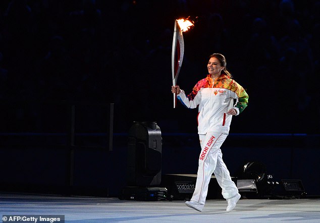 Alina Kabayeva runs with the Olympic torch during the Opening Ceremony of the Sochi Winter Olympics at the Fisht Olympic Stadium in 2014