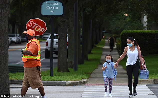 Schools around the United States are modifying their curriculum in response to the Black Lives Matter movement as students return following a summer of protest. Pictured, a mother walks her child to school on the first day of in-person classes in Orange County, Florida, Friday
