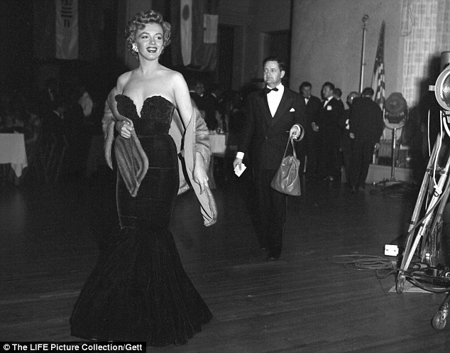Clad in a show-stopping red velvet dress and fur stole, a 25-year-old Marilyn glides across the floor of the Club Del Mar in Santa Monica, California January 1952 to receive one of her very first career awards