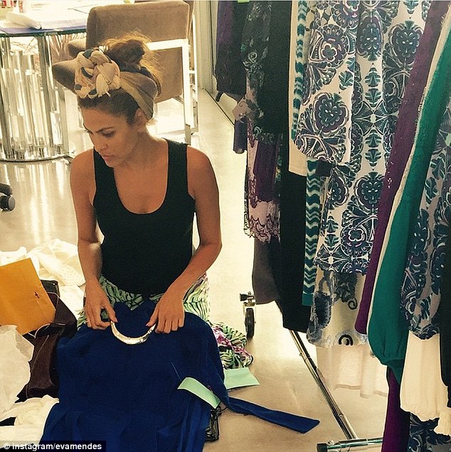 She loved what she does: In this image, Eva is looking at a blue dress she made as she sits next to a rack of clothes offered at New York & Company