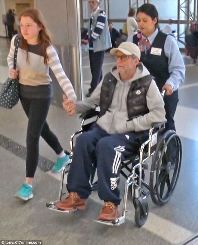 Wishing him good health: Wheelchair bound Eric Clapton, 71, looked frail  at LAX airport as he holds hands with his teenage daughter... after being forced to pull out of two gigs due to 
