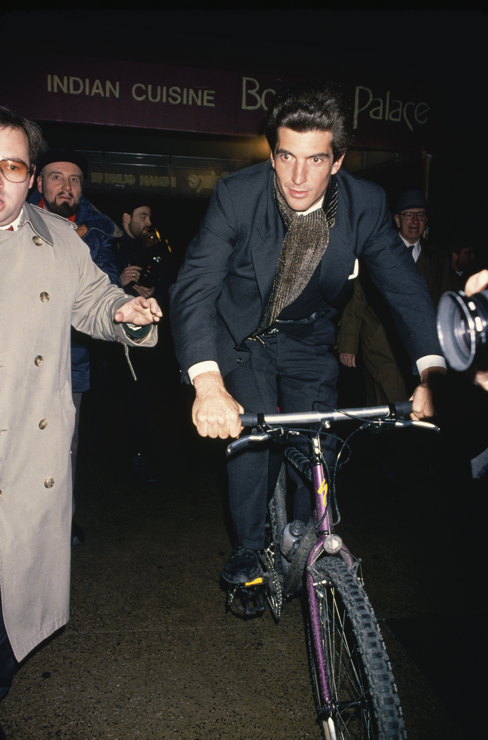 Джон Ф. Кеннеди-младший едет на велосипеде сквозь толпу папарацци