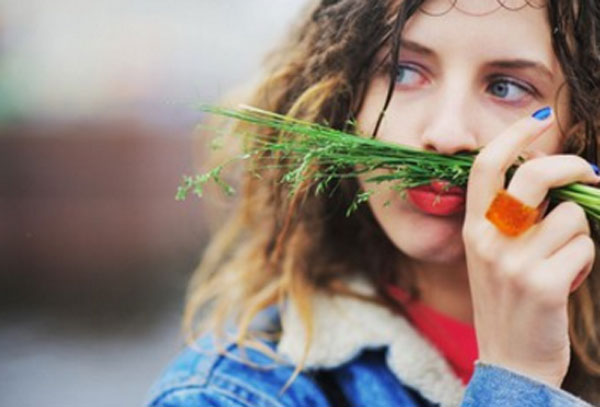 Девушка с кольцом из морковки. Держит зелень над губами, представляя, что это усы
