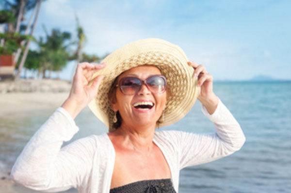 Женщина в шляпке идет по берегу и смеется