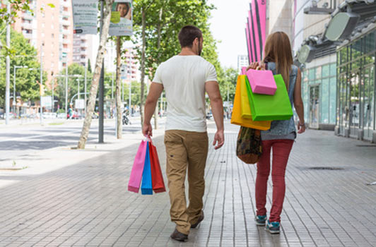 man following woman carrying her shopping bags
