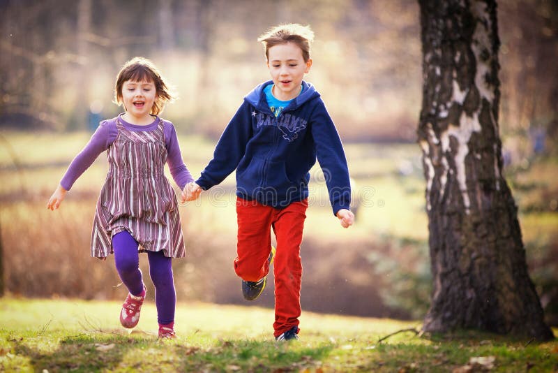 Brother and sister running. Siblings, brother and sister running in the forest royalty free stock photos