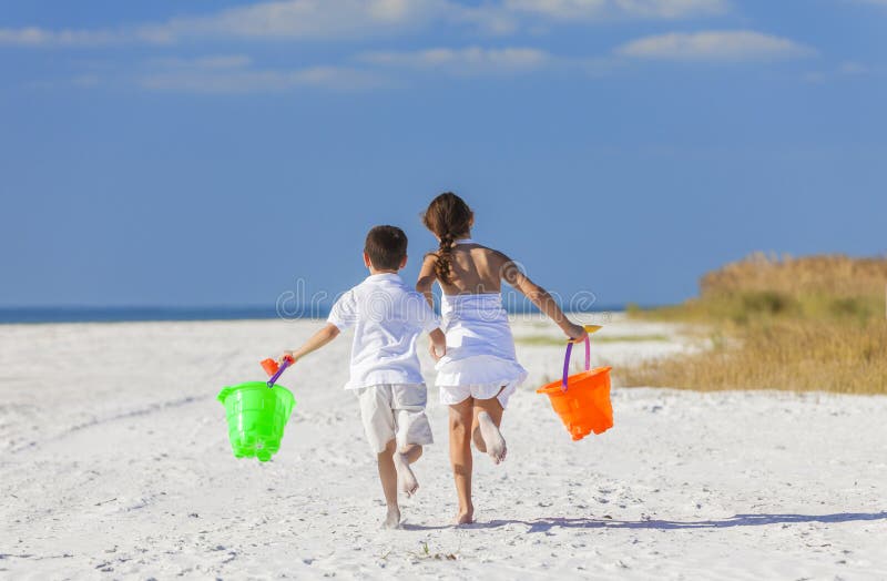 Children, Boy Girl Brother Sister Running Playing on Beach. Happy children, boy girl, brother and sister running and having fun playing in the sand on a beach royalty free stock photography