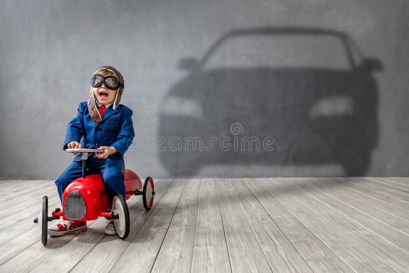 Happy child wants to race. Imagination, freedom and motivation concept. Happy child wants to race. Funny kid dreams about a car. Imagination, freedom and royalty free stock photo