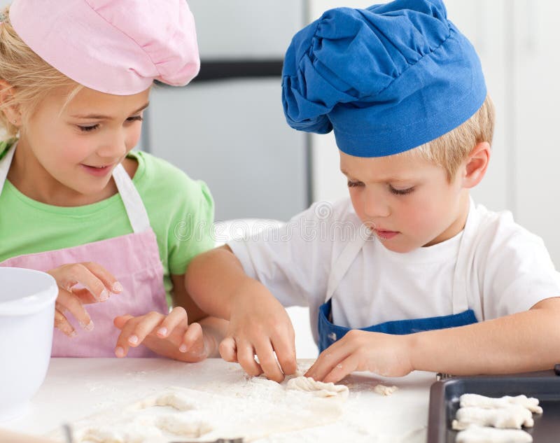 Young brother and sister kneading a dough. To make cakes in the kitchen royalty free stock photos