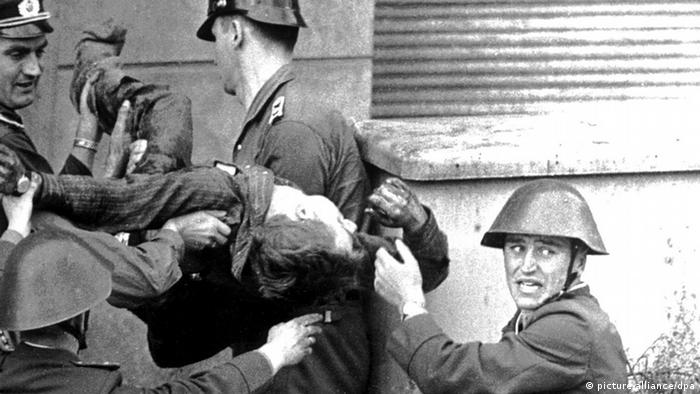 East German soldiers pick up Peter Fechter after he was shot while climbing over the Berlin Wall (picture-alliance/dpa)