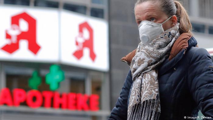 Женщина в Берлине идет по улице с защитной маской на лице, которая, как она надеется, поможет ей избежать заражения коронавирусом.